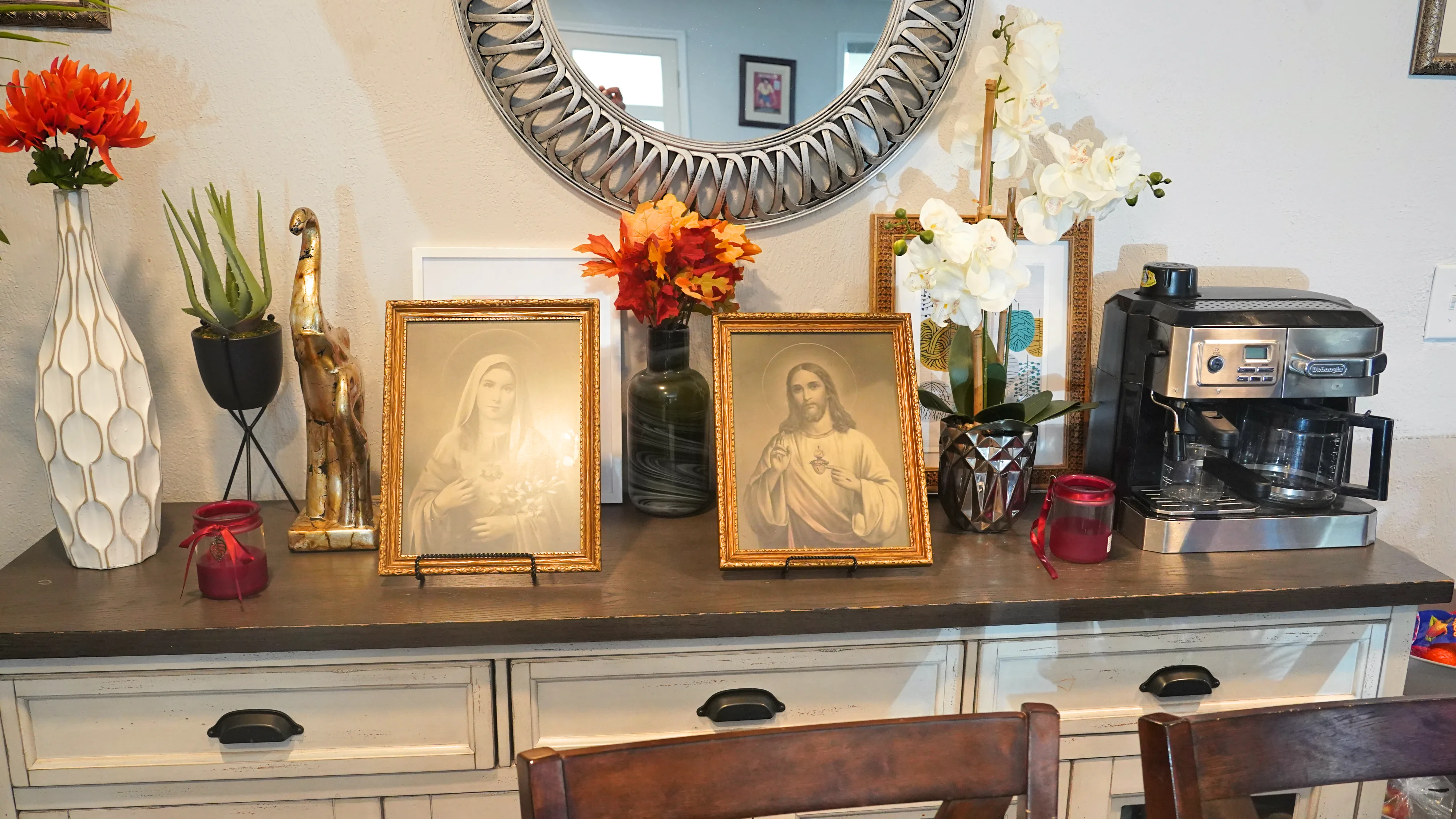 Decorative sideboard with framed artwork, flowers, and mirror