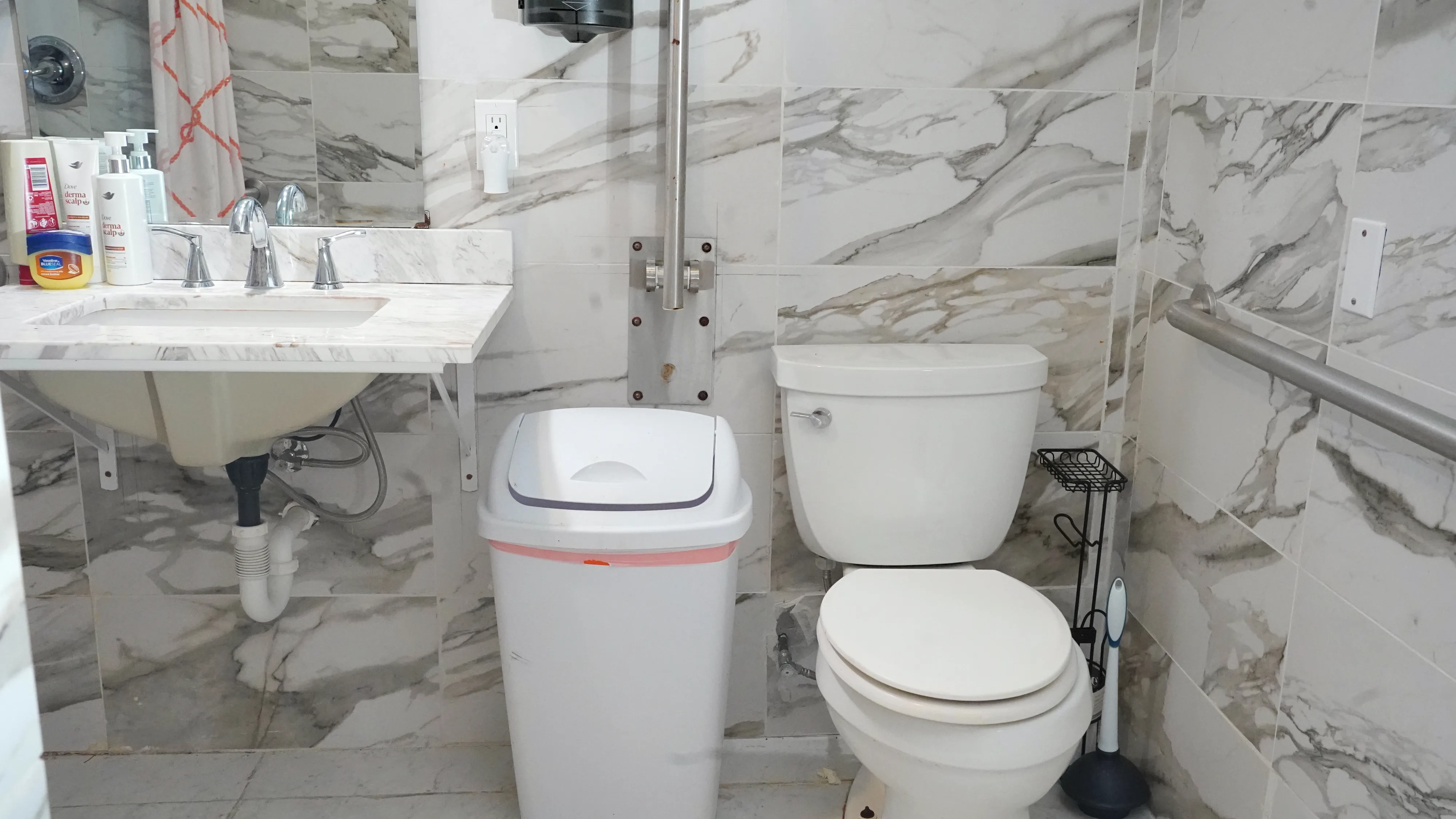 Bathroom with marble walls, vanity sink, and safety grab bar