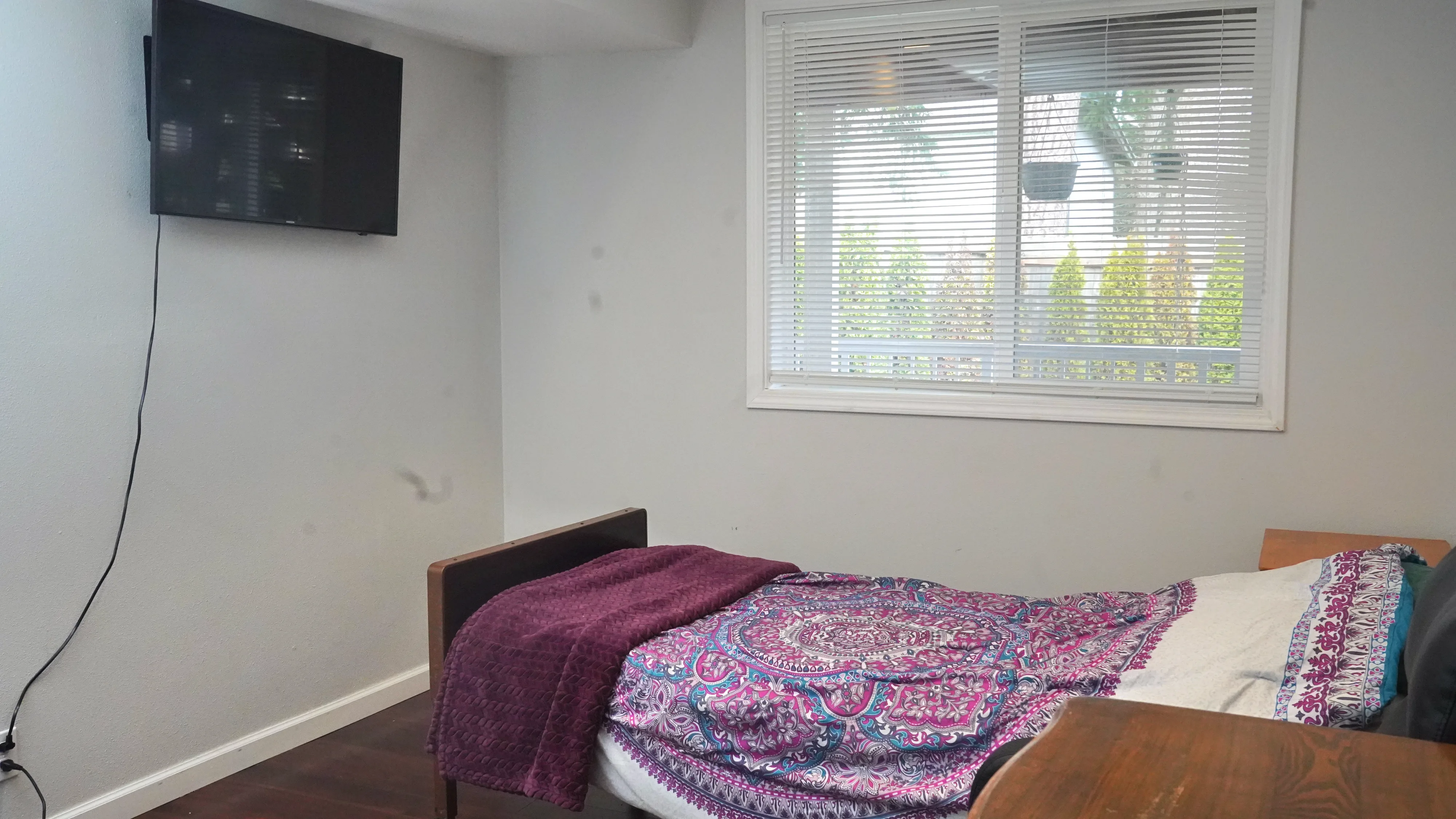 Resident bedroom with wall-mounted TV and garden window view