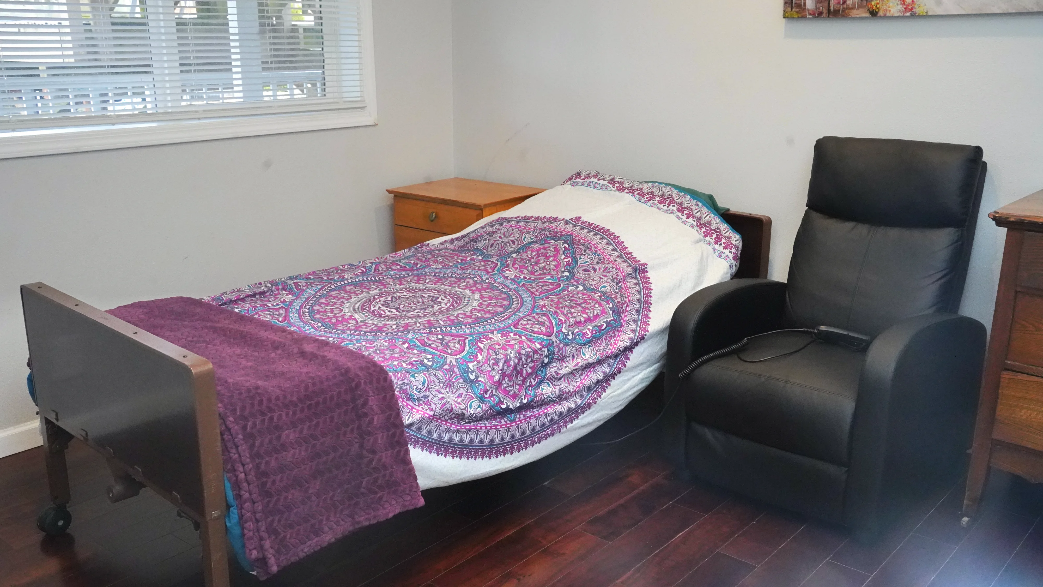 Resident bedroom with adjustable bed, recliner, and nightstand